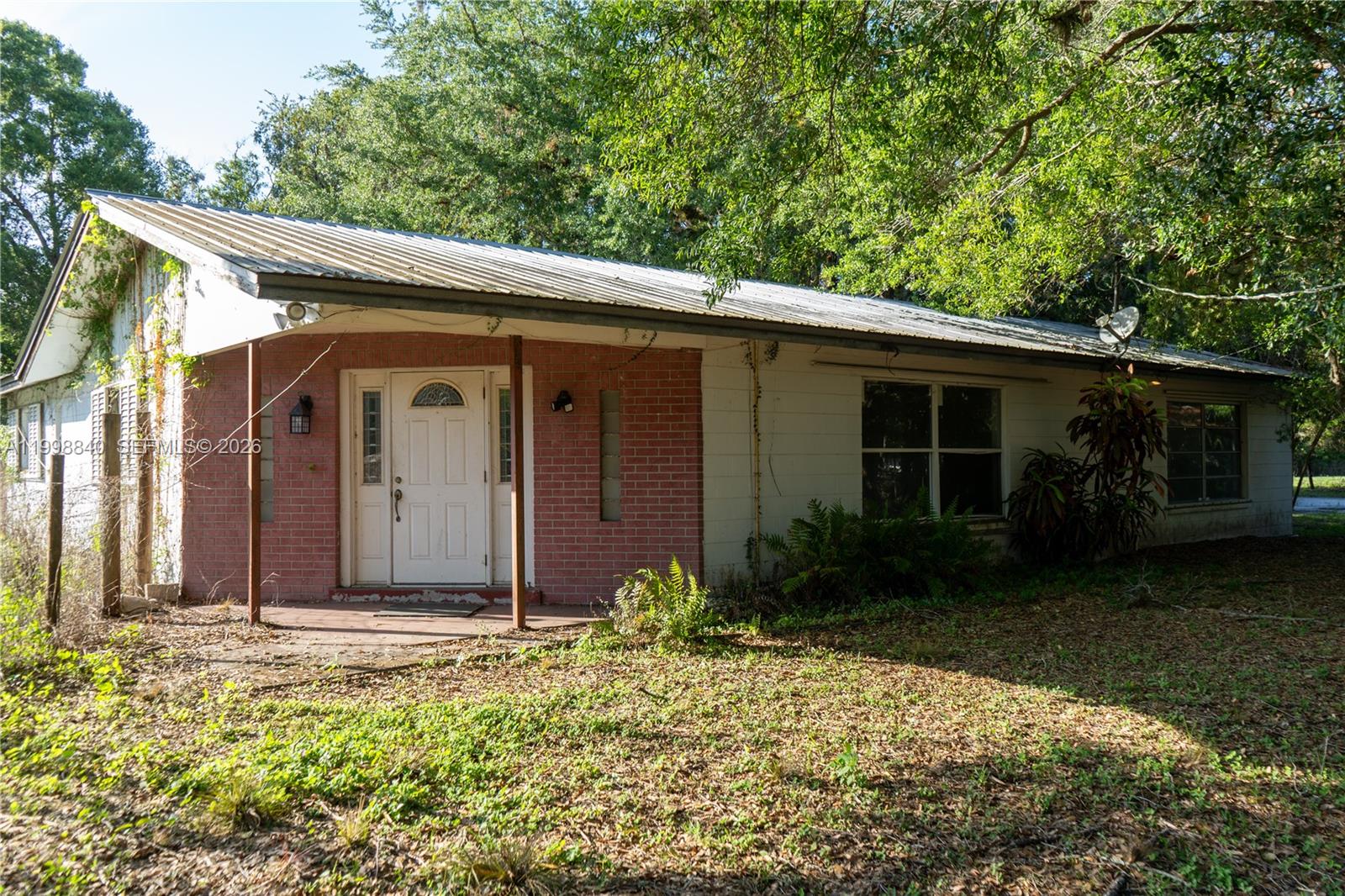 A single-story house with a metal roof, brick facade, and a covered front porch — 120 CR 78, La Belle FL 33935, LA BELLE, FL
