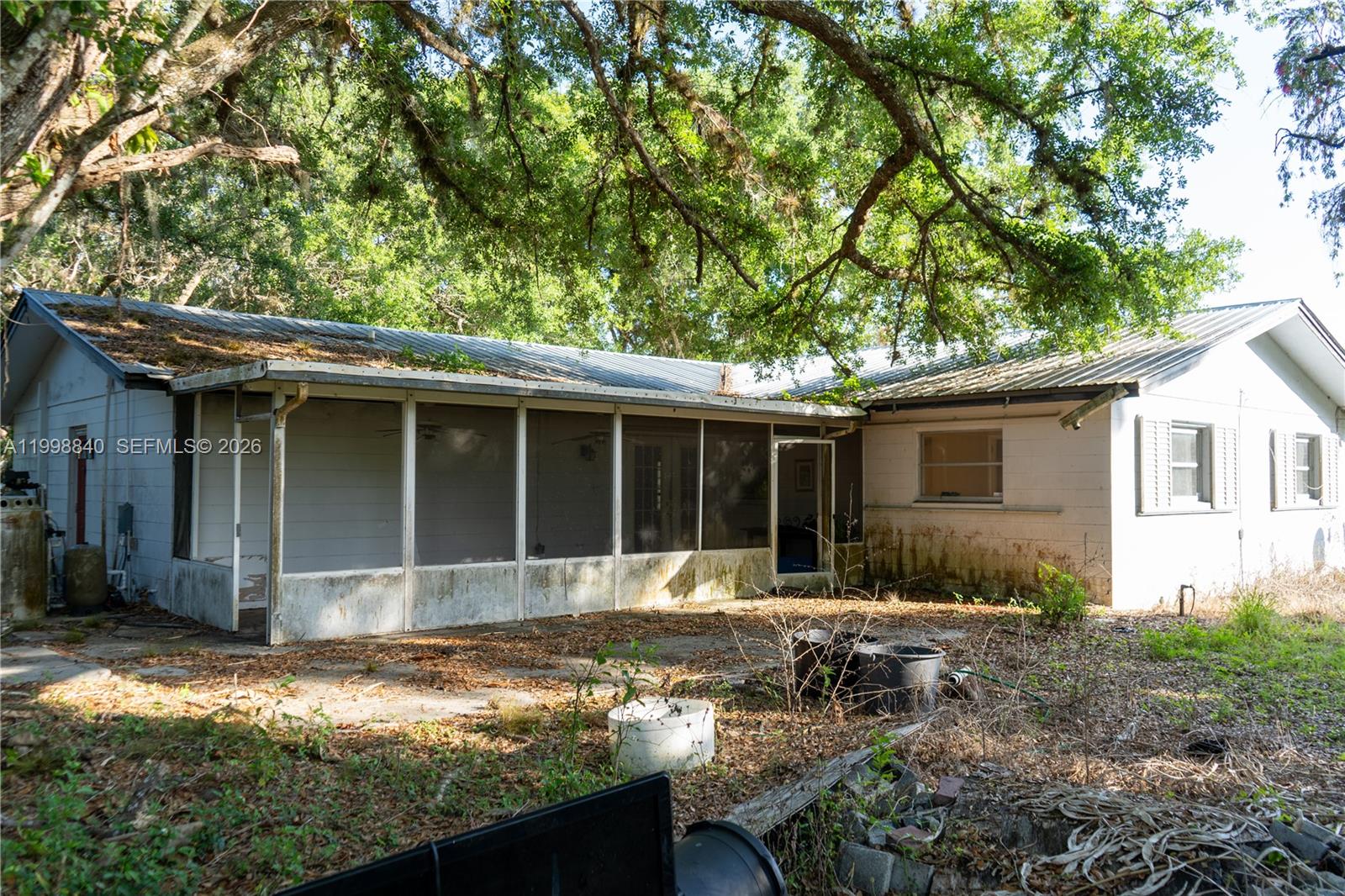The exterior of a single-story house features a screened-in porch and a metal roof — 120 CR 78, La Belle FL 33935, LA BELLE, FL
