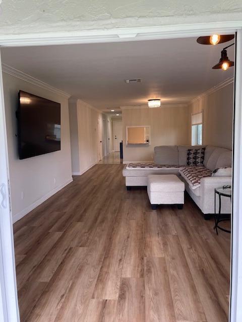 A living room features light wood-look flooring, a wall-mounted television, and a sectional sofa — 5655 Via Delray Boulevard, Delray Beach FL 33484, DELRAY BEACH, FL