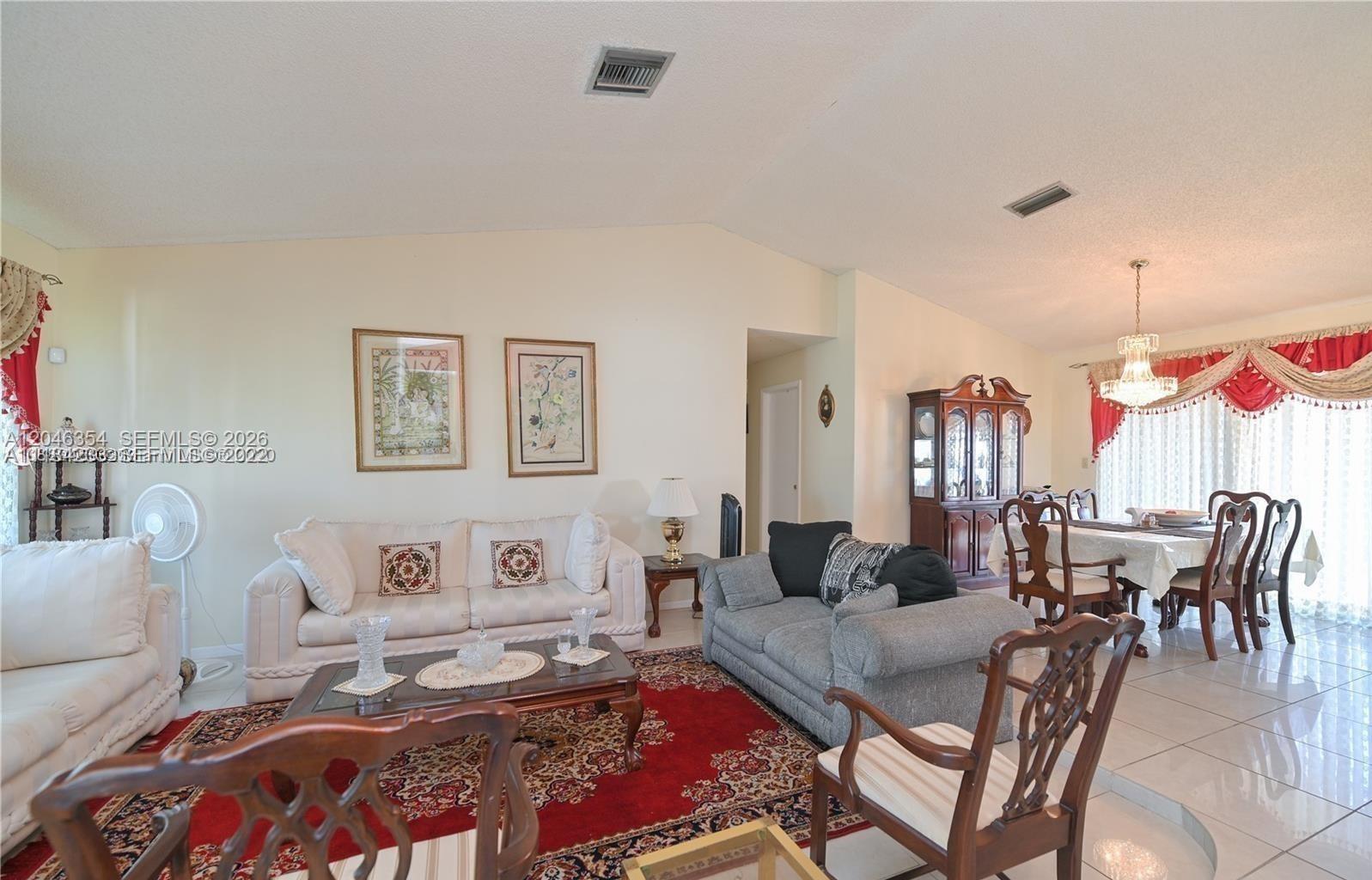 A living and dining area features white tile floors, a red area rug, and vaulted ceilings — 9612 SW 117th Ave # 9612, Miami FL 33186, MIAMI, FL