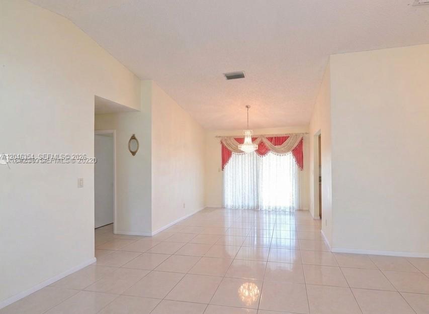 A dining area with light tile flooring, a chandelier, and sliding glass doors with curtains — 9612 SW 117th Ave # 9612, Miami FL 33186, MIAMI, FL