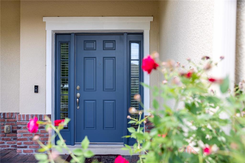 A blue front door with sidelights is framed by a white trim and brick accents — 4810 LAKE MILLY DRIVE, ORLANDO, FL