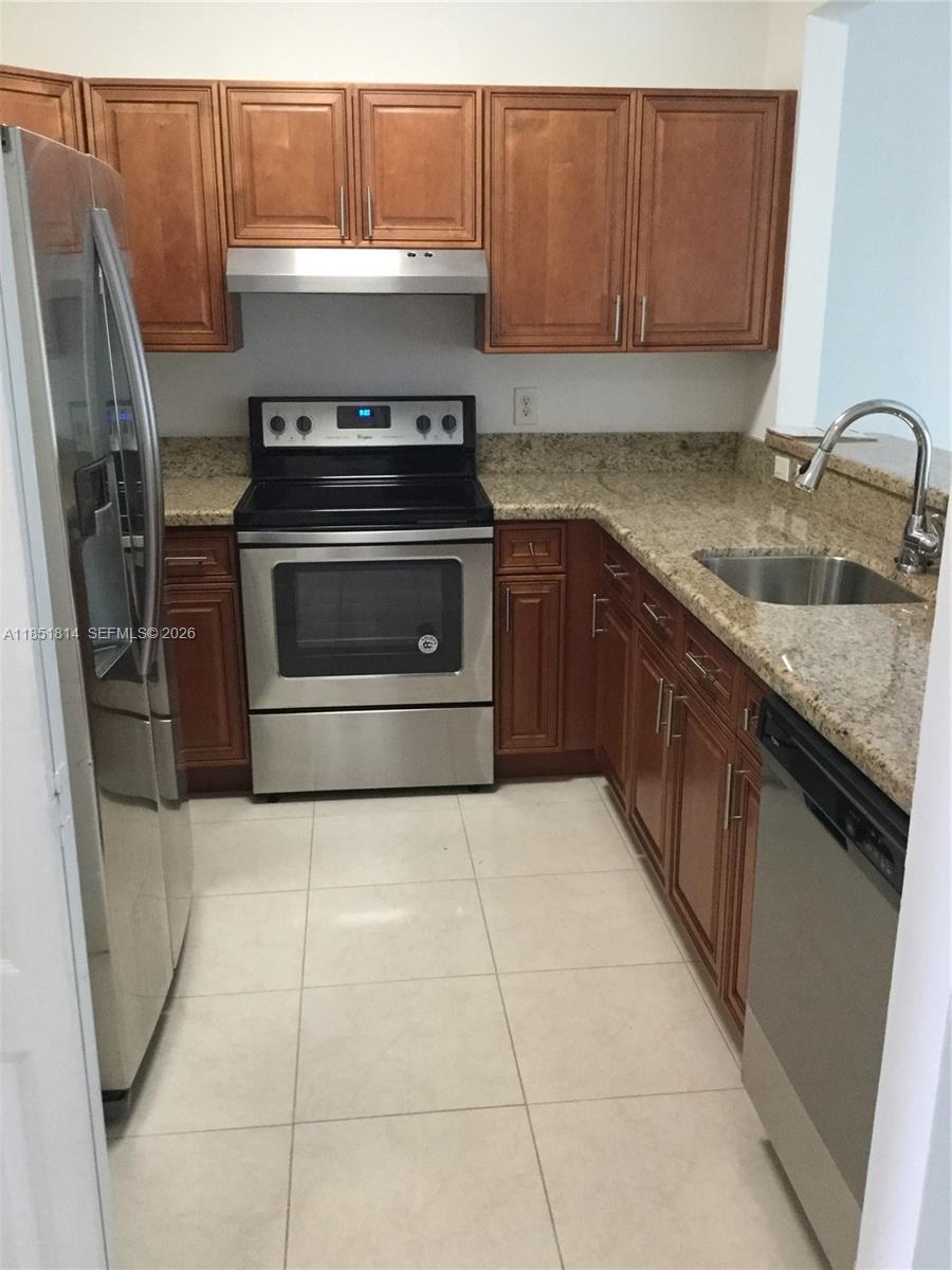 A kitchen features wood cabinets, granite countertops, stainless steel appliances, and light-colored tile flooring — 2885 SW 127th Ave, Miramar FL 33027, MIRAMAR, FL