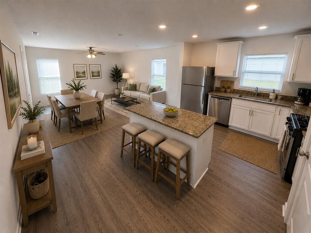 An open-concept kitchen, dining area, and living room featuring wood-look flooring and granite countertops — 233 KENSINGTON VIEW BOULEVARD, WINTER HAVEN, FL