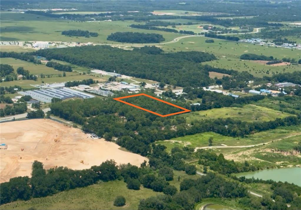 An aerial view shows a rectangular plot of land outlined in orange amidst wooded areas — SW 60TH AVENUE, OCALA, FL