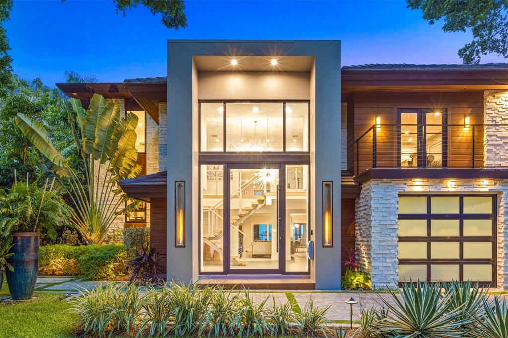 A modern two-story house with a stone facade, glass garage doors, and a large entryway — 1365 BRIGHTWATERS BOULEVARD NE, ST PETERSBURG, FL