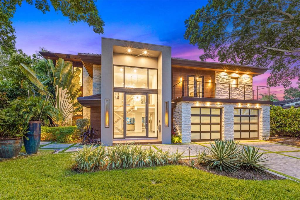 A modern two-story house exterior features a glass-paneled front door, stone accents, and wood siding — 1365 BRIGHTWATERS BOULEVARD NE, ST PETERSBURG, FL