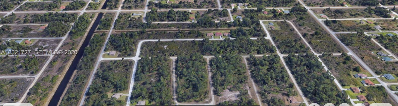 An aerial view shows a residential area with undeveloped wooded lots and paved roads — 322 Lubdel Ave S, Lehigh Acres FL 33974, LEHIGH ACRES, FL