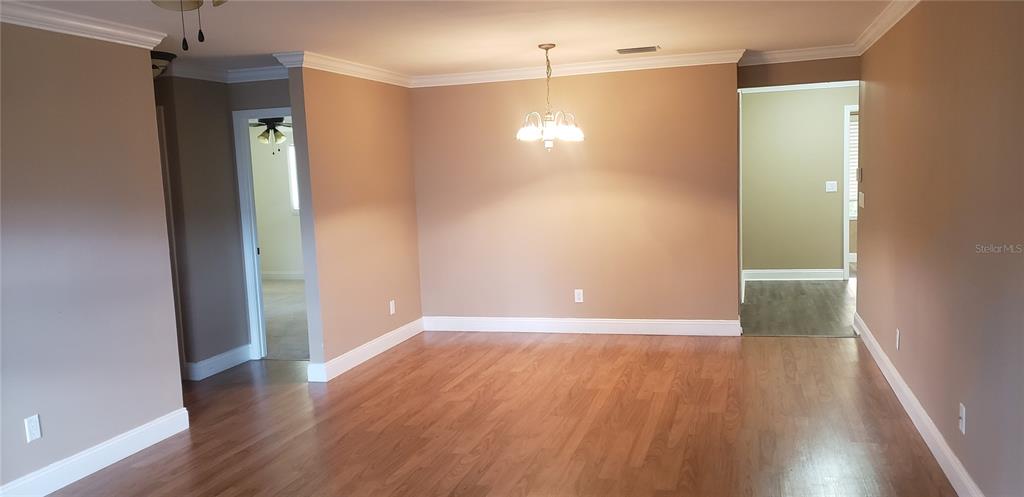 A dining area with light wood flooring, beige walls, and a central chandelier — 9142 SW 82ND TERRACE UNIT C, OCALA, FL