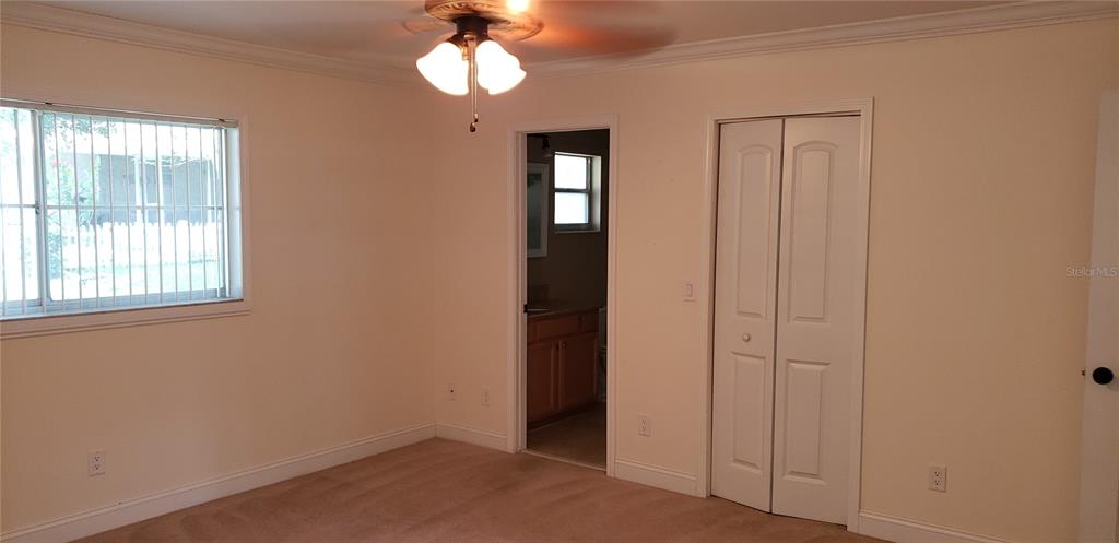 A bedroom features beige carpet, a ceiling fan, a window with security bars, and a closet — 9142 SW 82ND TERRACE UNIT C, OCALA, FL