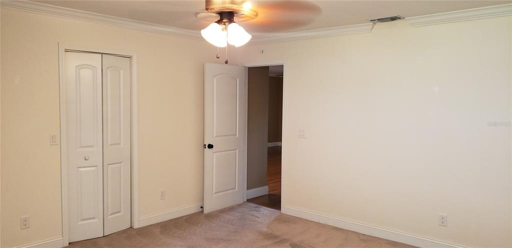 A bedroom features beige carpet, cream-colored walls, a ceiling fan, and two white doors — 9142 SW 82ND TERRACE UNIT C, OCALA, FL