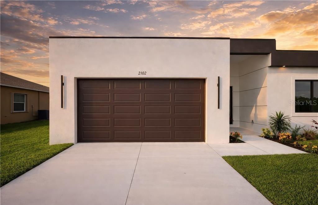 A modern house exterior features a white facade, a brown garage door, and a concrete driveway — 2102 NW 25TH PLACE, CAPE CORAL, FL