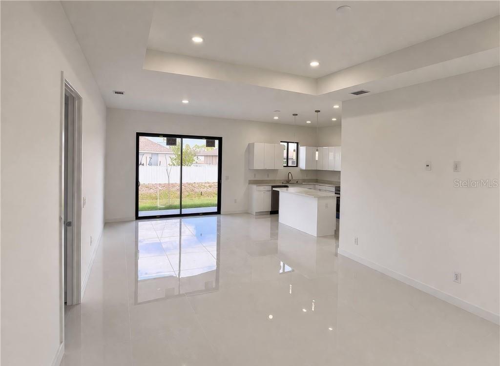 A bright, open-concept kitchen and living area features white cabinetry, a center island, and tile flooring — 2102 NW 25TH PLACE, CAPE CORAL, FL