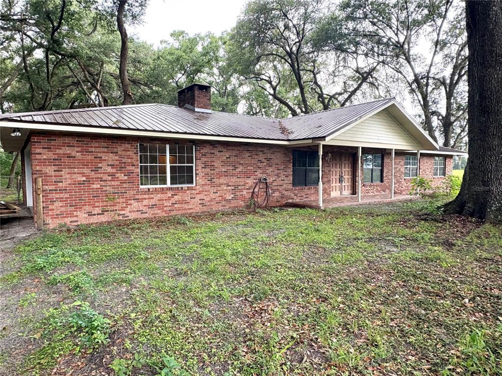 A single-story brick house with a metal roof and a covered front porch — 7532 SW 122ND STREET, GAINESVILLE, FL