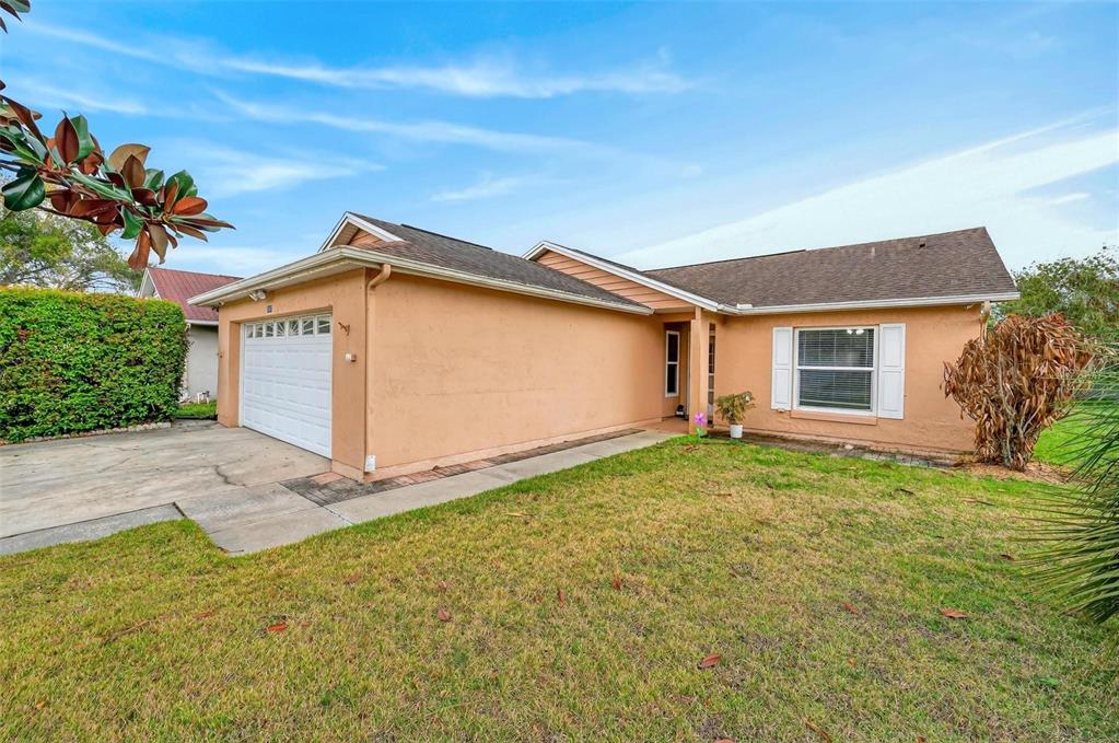 A single-story peach-colored house with a white garage door and a front lawn — 5107 DEER CREEK DRIVE, ORLANDO, FL