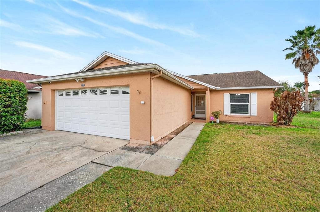 A single-story peach-colored house with a white garage door and a front lawn — 5107 DEER CREEK DRIVE, ORLANDO, FL