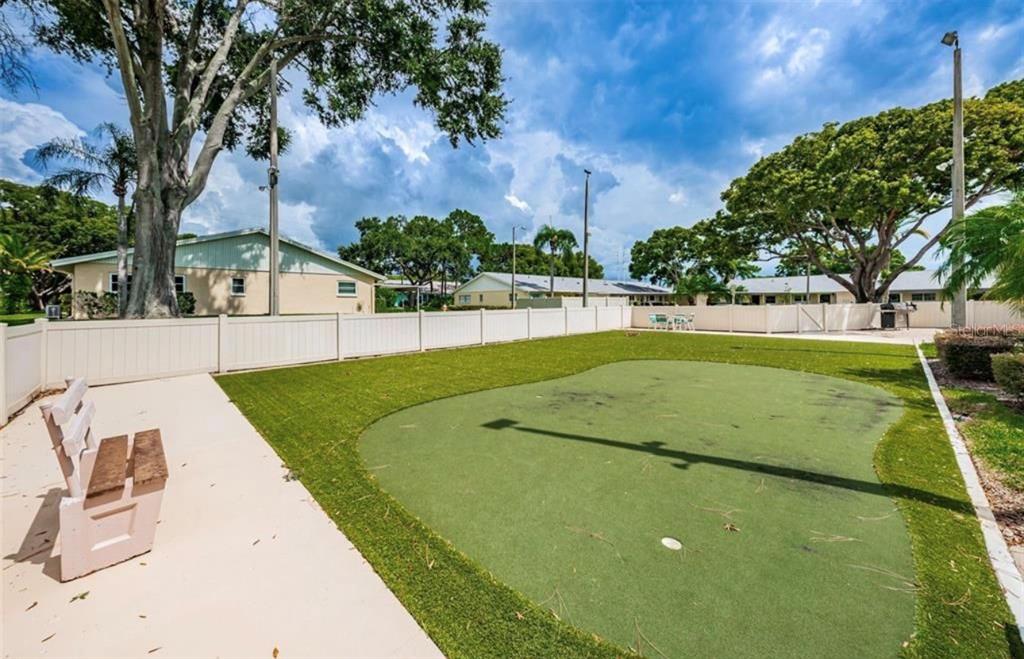 A backyard putting green with artificial turf is enclosed by a white vinyl fence — 2465 NORTHSIDE DRIVE UNIT 2204, CLEARWATER, FL