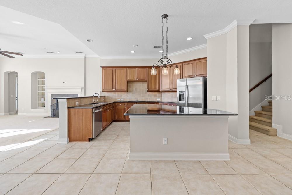 A kitchen features wood cabinets, dark countertops, a central island, and tile flooring — 25515 HAWKS RUN LANE, SORRENTO, FL