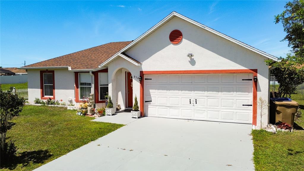A single-story house with a white stucco exterior, orange trim, and a two-car garage — 852 FRANCONVILLE COURT, KISSIMMEE, FL