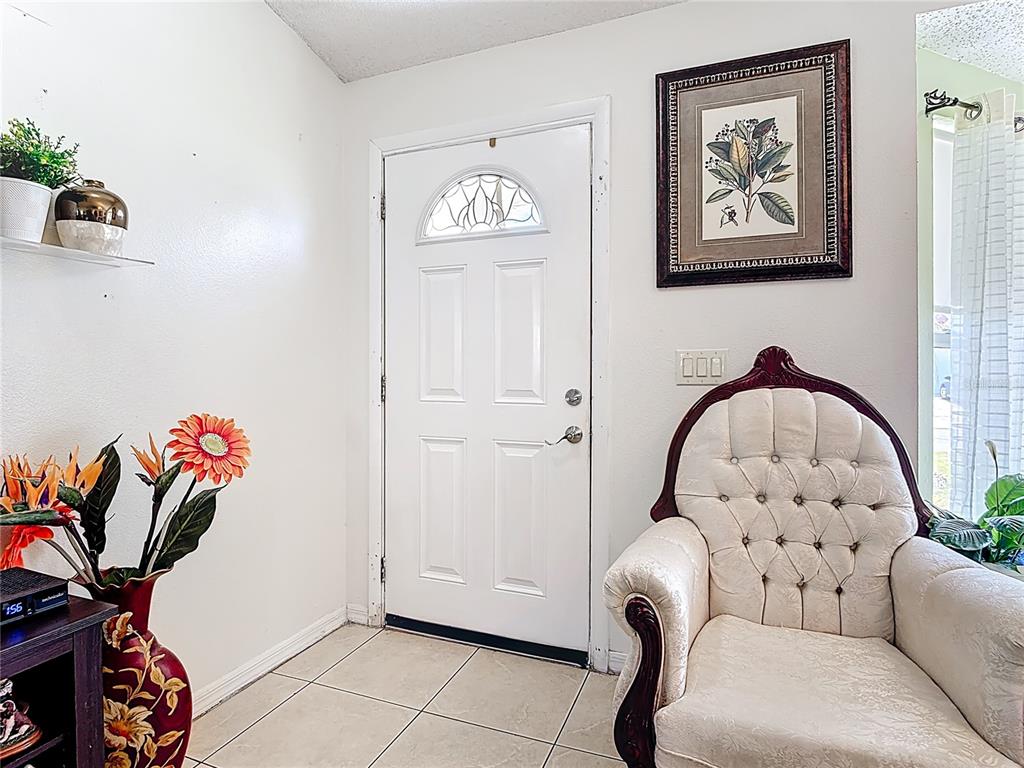 An entryway features a white front door, a tufted armchair, and a framed botanical print — 852 FRANCONVILLE COURT, KISSIMMEE, FL