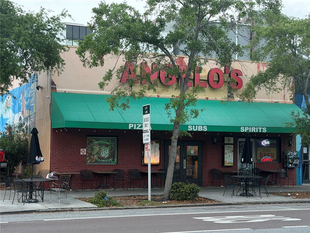 The exterior of Angelo's restaurant features a green awning, brick facade, and outdoor patio seating — 532 1ST AVENUE N, ST PETERSBURG, FL