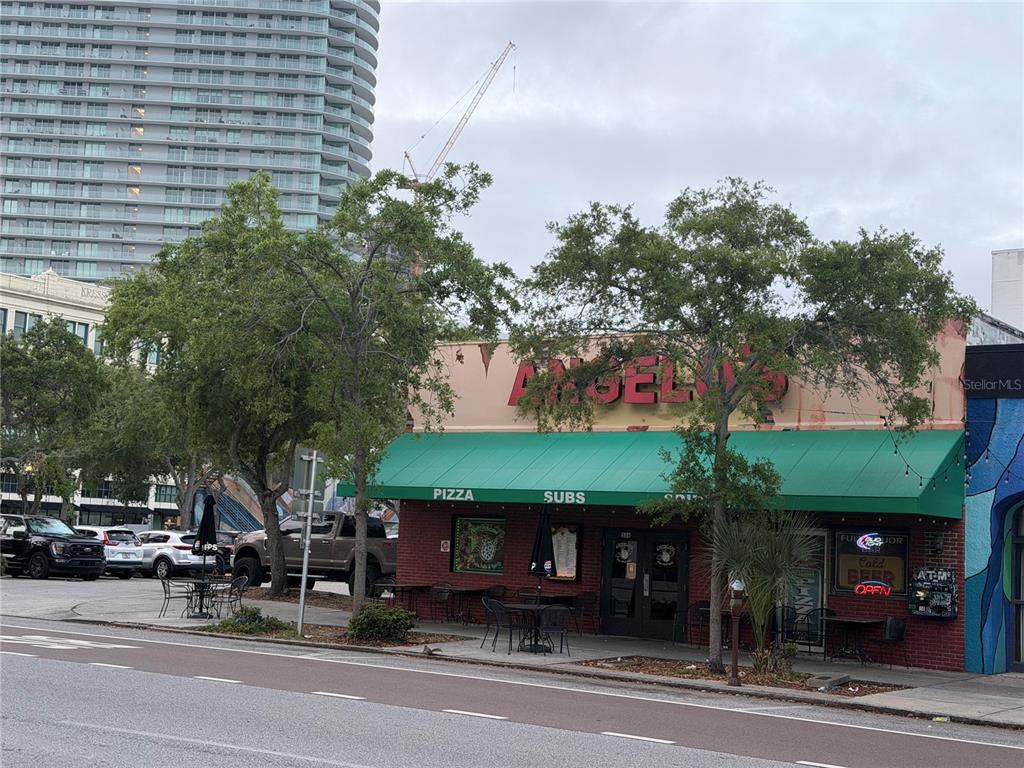 A street-level view of a brick restaurant building with a green awning and outdoor seating — 532 1ST AVENUE N, ST PETERSBURG, FL