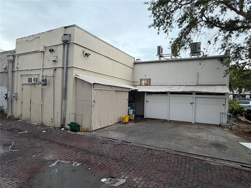 The exterior of a commercial building features a brick alleyway, metal awnings, and white doors — 532 1ST AVENUE N, ST PETERSBURG, FL