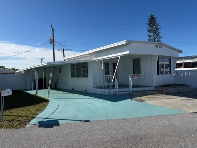 A white mobile home features a teal-painted driveway and a covered carport — 308 51ST AVENUE DRIVE W, BRADENTON, FL
