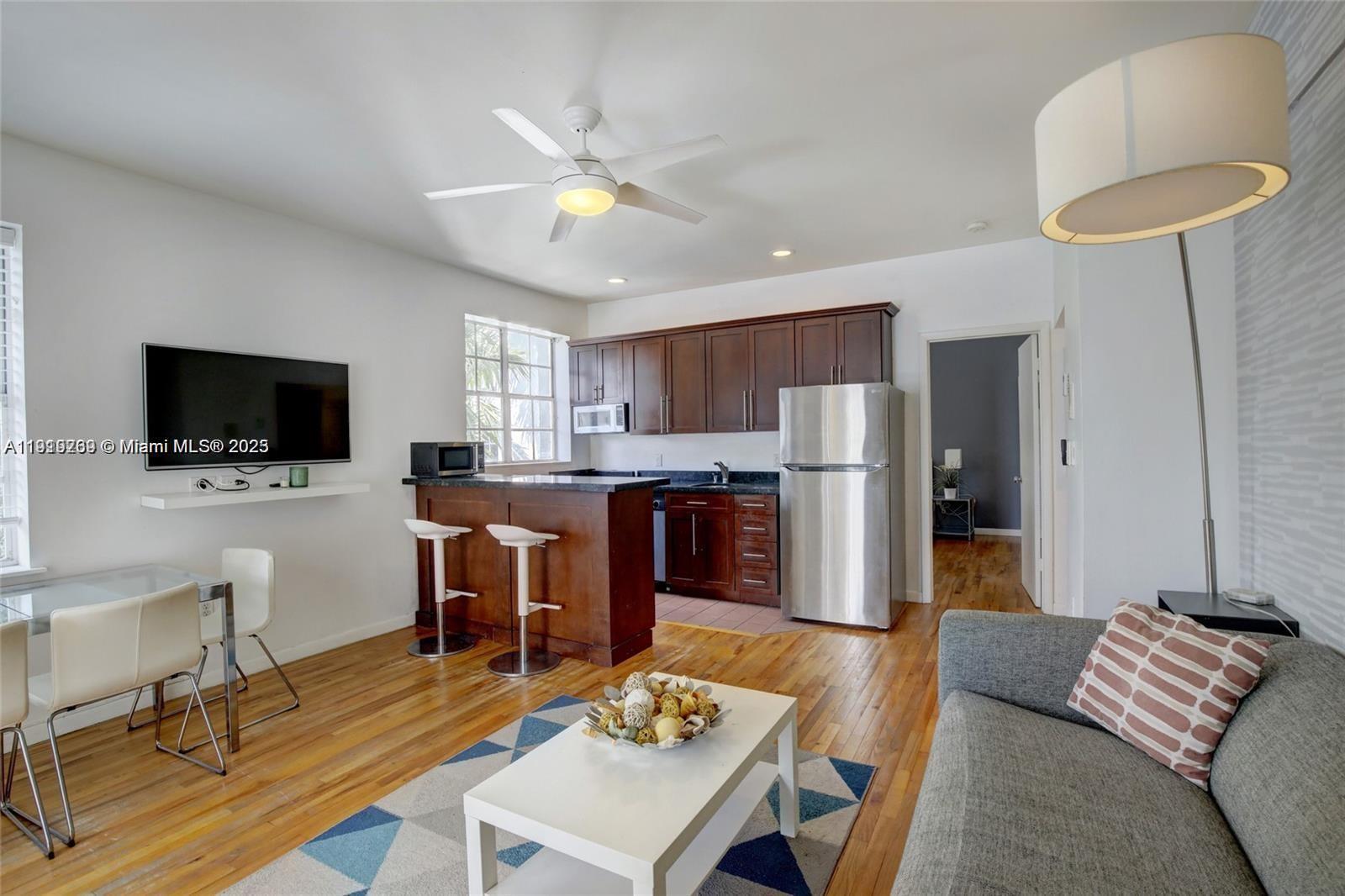 This open-concept living area features a kitchen with dark wood cabinets and a breakfast bar — 1127 Euclid Ave # 206, Miami Beach FL 33139, MIAMI BEACH, FL
