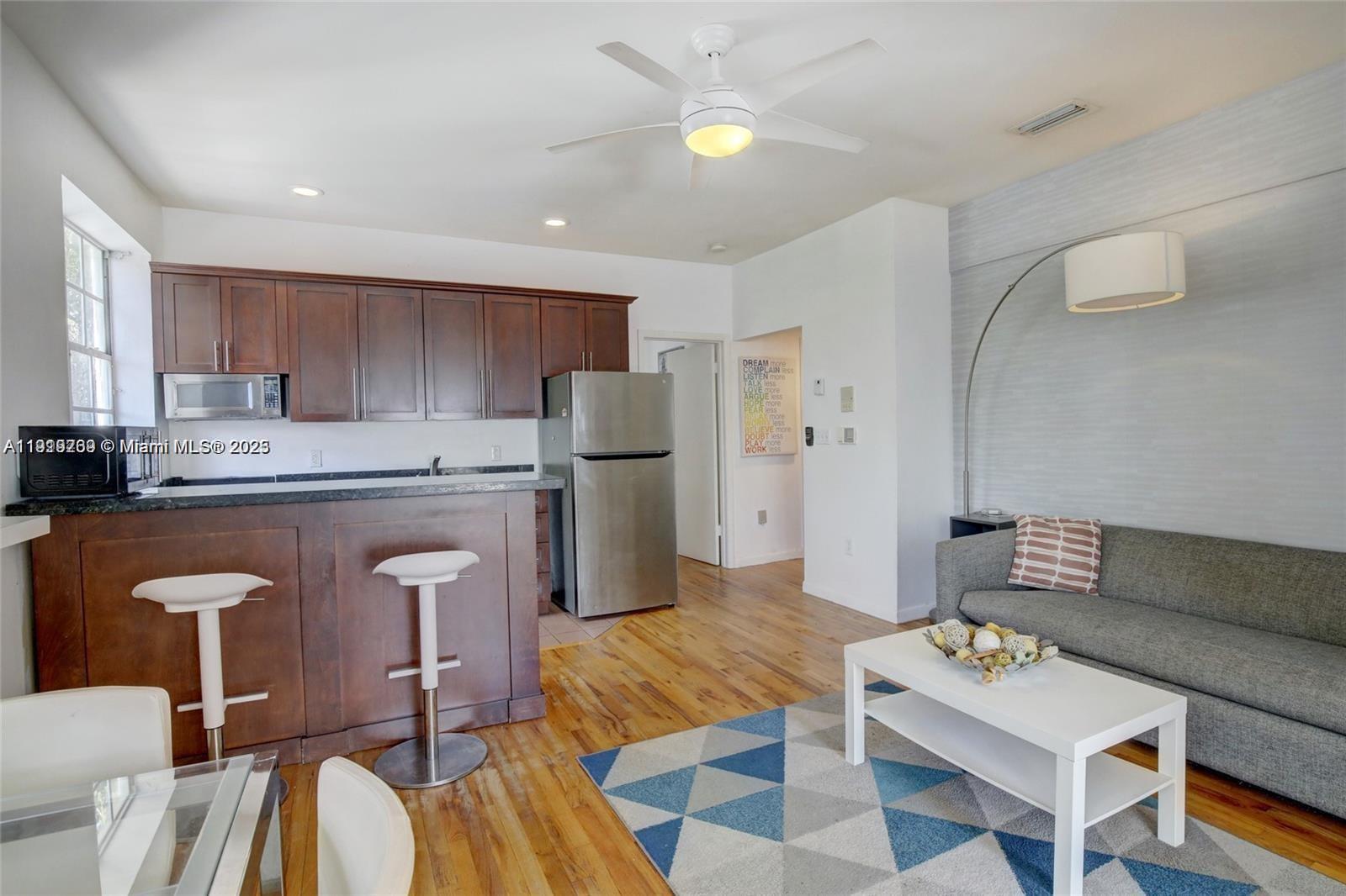 An open-concept living area features a kitchen with dark wood cabinets and a gray sofa — 1127 Euclid Ave # 206, Miami Beach FL 33139, MIAMI BEACH, FL