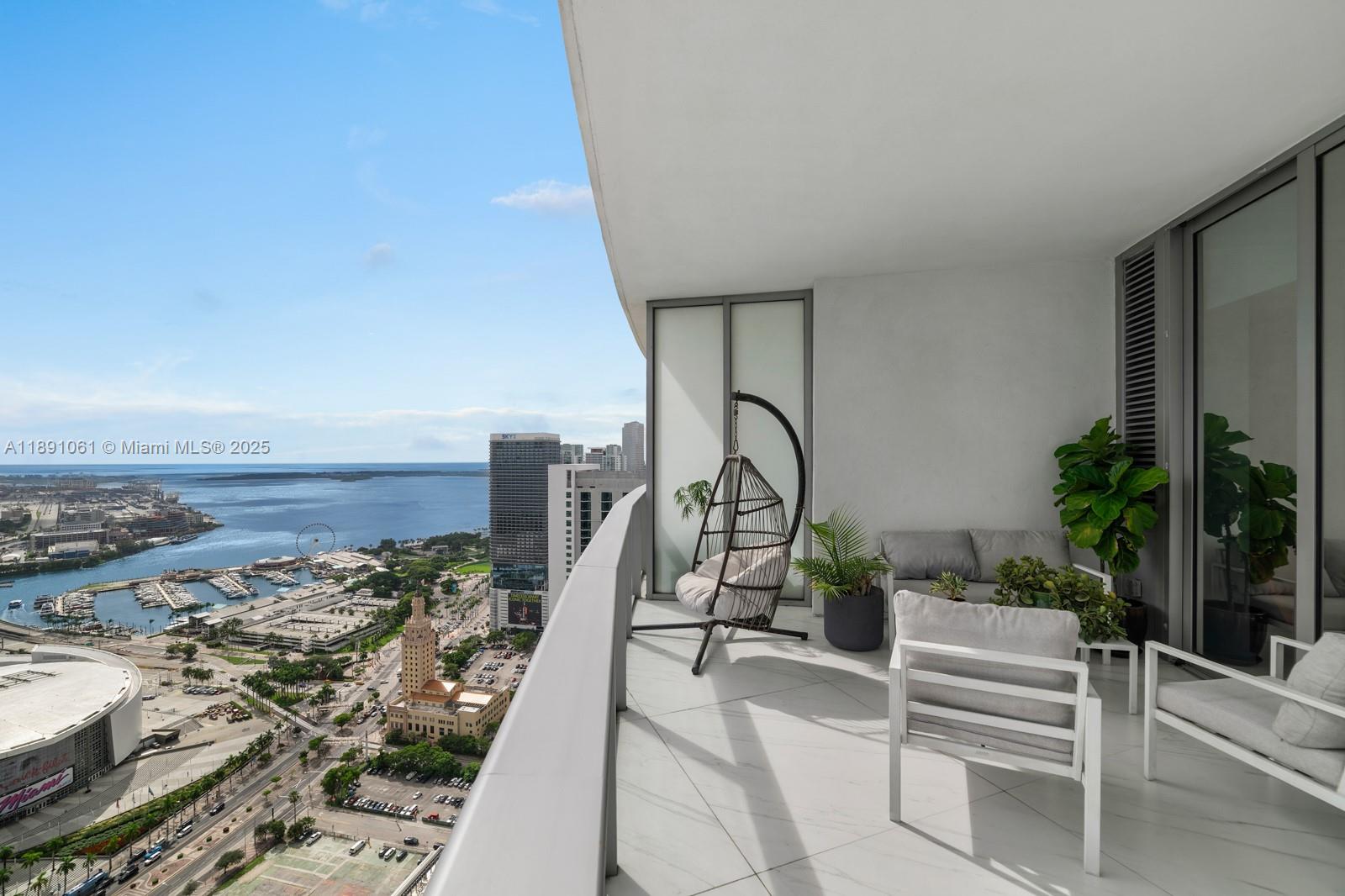 A high-rise balcony features outdoor furniture and a panoramic view of the Miami waterfront — 851 NE 1st Ave # 4403, Miami FL 33132, MIAMI, FL