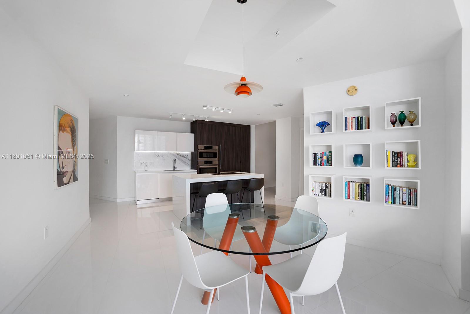 A modern kitchen and dining area features white cabinetry, a glass table, and wall-mounted shelving — 851 NE 1st Ave # 4403, Miami FL 33132, MIAMI, FL