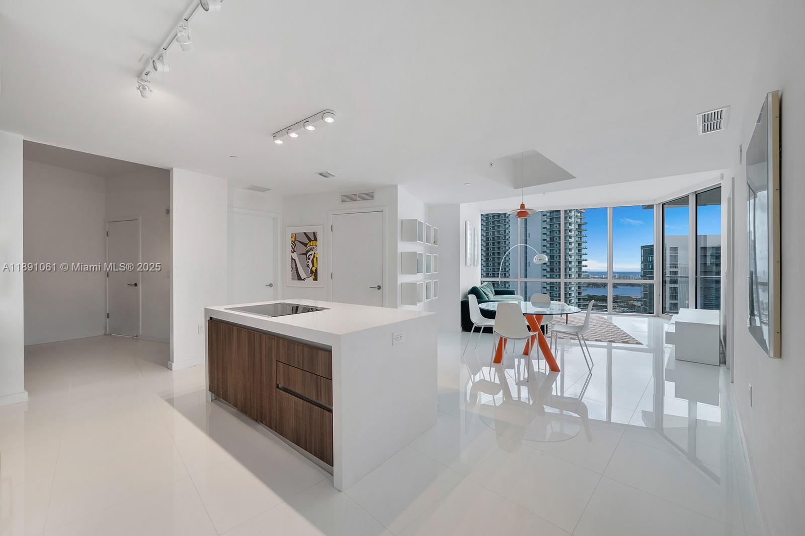 A modern kitchen island with wood cabinetry sits in an open-concept living area with views — 851 NE 1st Ave # 4403, Miami FL 33132, MIAMI, FL