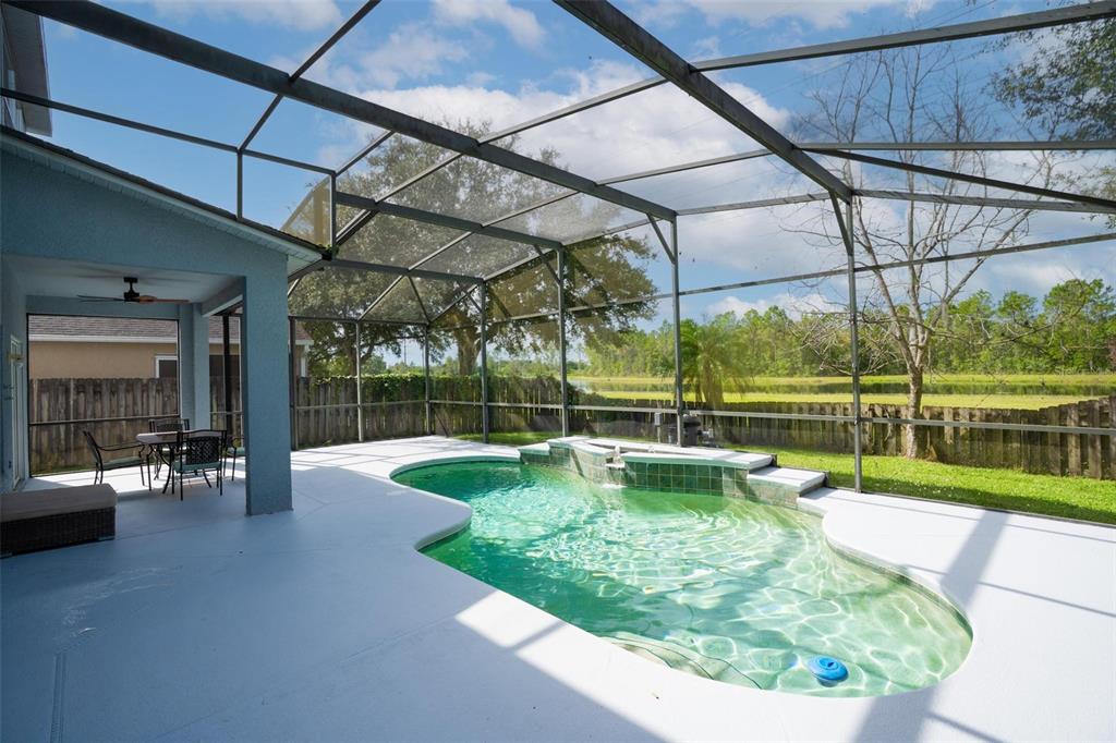 A screened-in patio features a swimming pool with a raised spa and a covered seating area — 1892 HAMMOCK MOSS DRIVE, ORLANDO, FL