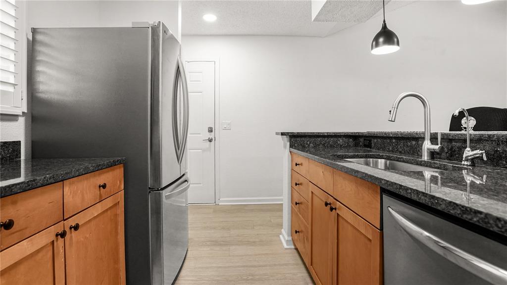 A kitchen features stainless steel appliances, wood cabinets, and dark granite countertops — 2500 WINDING CREEK BOULEVARD UNIT I205, CLEARWATER, FL