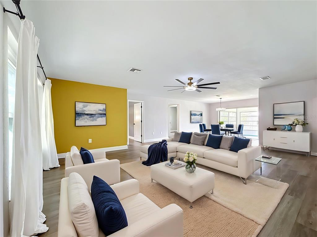 A spacious living room features a yellow accent wall, white sectional sofa, and wood flooring — 1405 OVERCASH DRIVE, DUNEDIN, FL