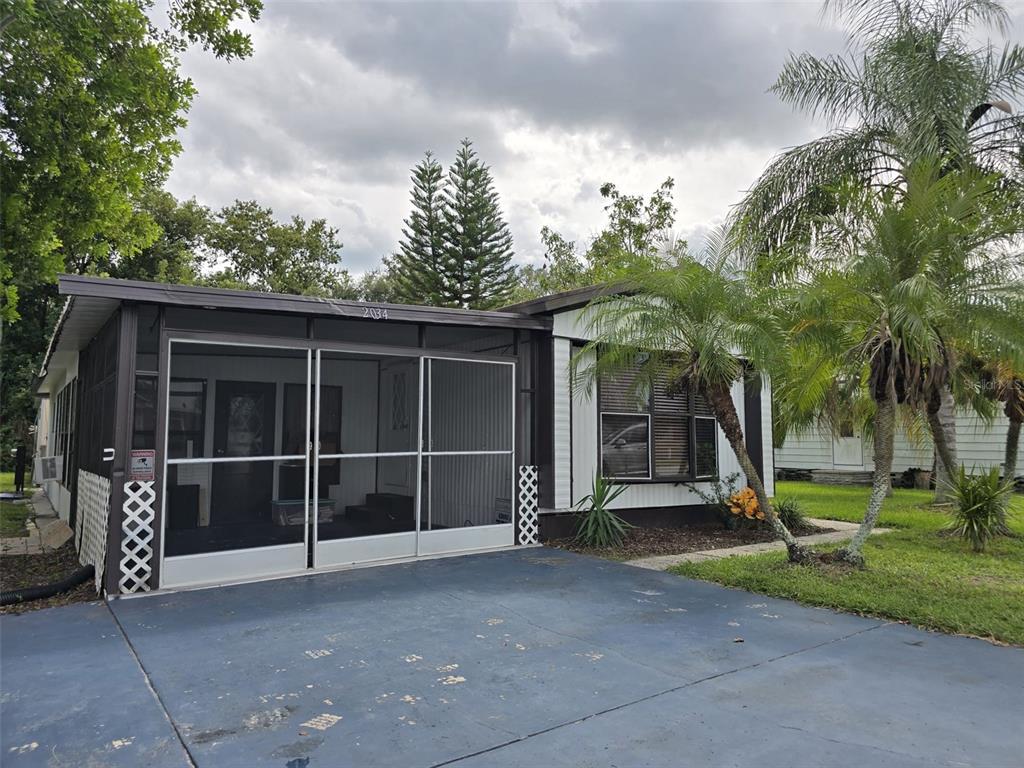 A single-story mobile home features a screened-in front porch and a blue painted driveway — 2034 THELMA DRIVE, LAKE ALFRED, FL