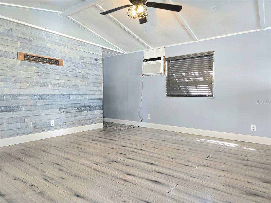 A room with light wood-look flooring, a gray accent wall, and a window air conditioner — 2034 THELMA DRIVE, LAKE ALFRED, FL