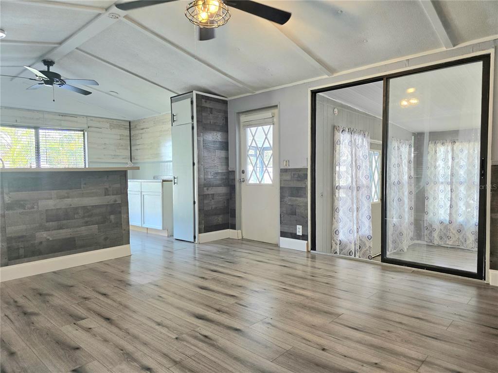A living area features wood-look flooring, gray shiplap accents, a ceiling fan, and sliding glass doors — 2034 THELMA DRIVE, LAKE ALFRED, FL