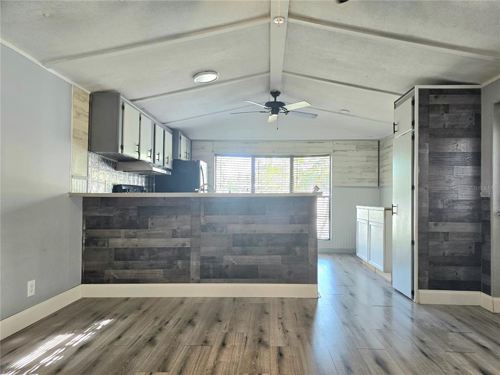 A kitchen with a wood-paneled breakfast bar, white cabinets, and light wood-look flooring — 2034 THELMA DRIVE, LAKE ALFRED, FL
