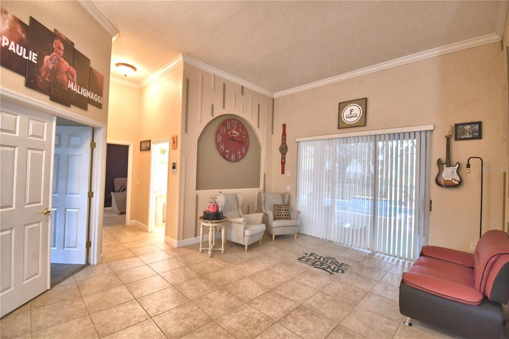 A living room features tile flooring, two armchairs, a red sofa, and boxing-themed wall decor — 1 LAKE ELOISE LANE, WINTER HAVEN, FL