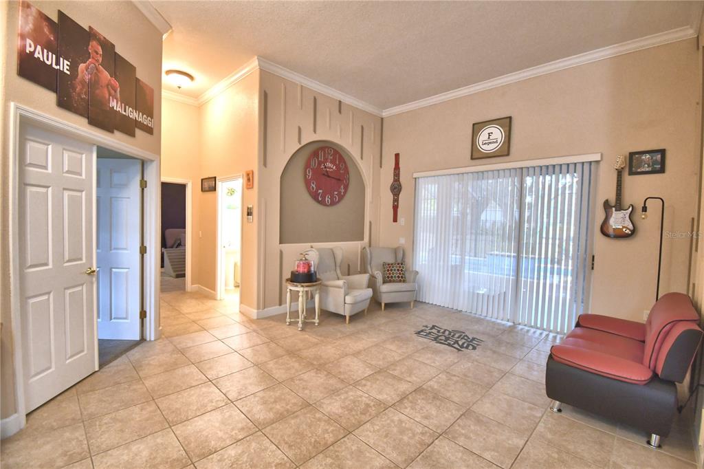 A tiled living area features a large wall clock, two armchairs, and a red sofa — 1 LAKE ELOISE LANE, WINTER HAVEN, FL