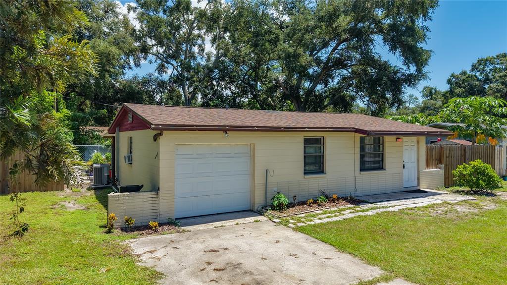 A single-story house with a white garage door, tan siding, and a brown shingled roof — 8653 69TH STREET N, PINELLAS PARK, FL