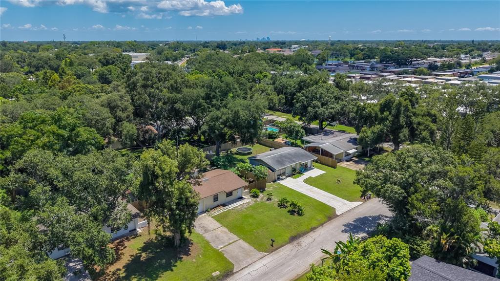 An aerial view shows two single-story houses with driveways surrounded by dense trees and lawns — 8653 69TH STREET N, PINELLAS PARK, FL