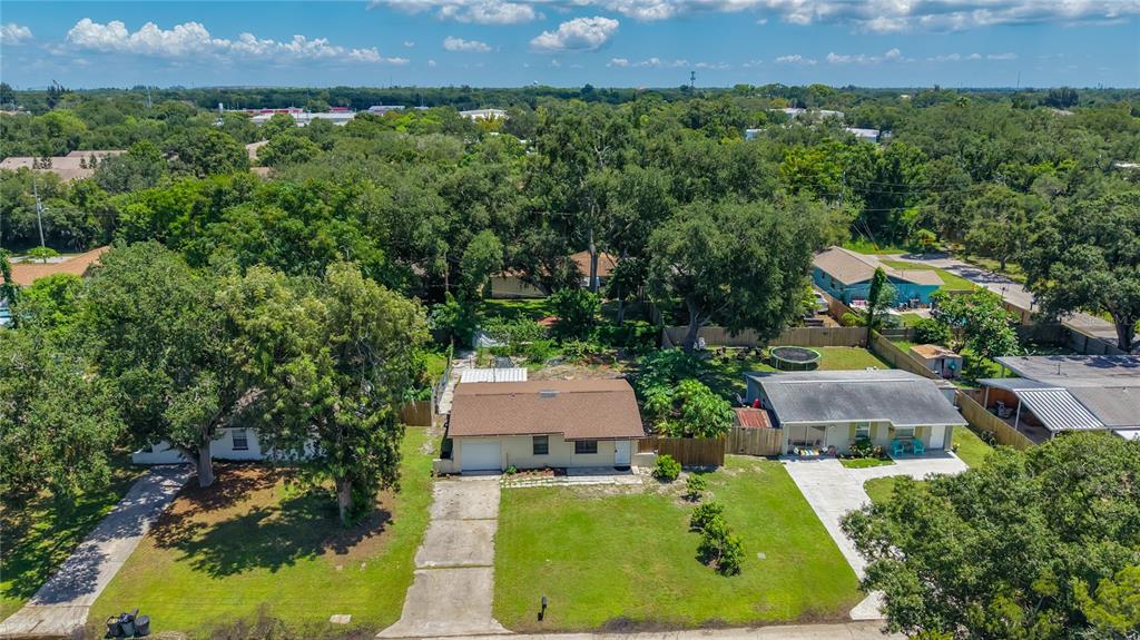 An aerial view shows two single-story houses with brown roofs surrounded by trees and lawns — 8653 69TH STREET N, PINELLAS PARK, FL