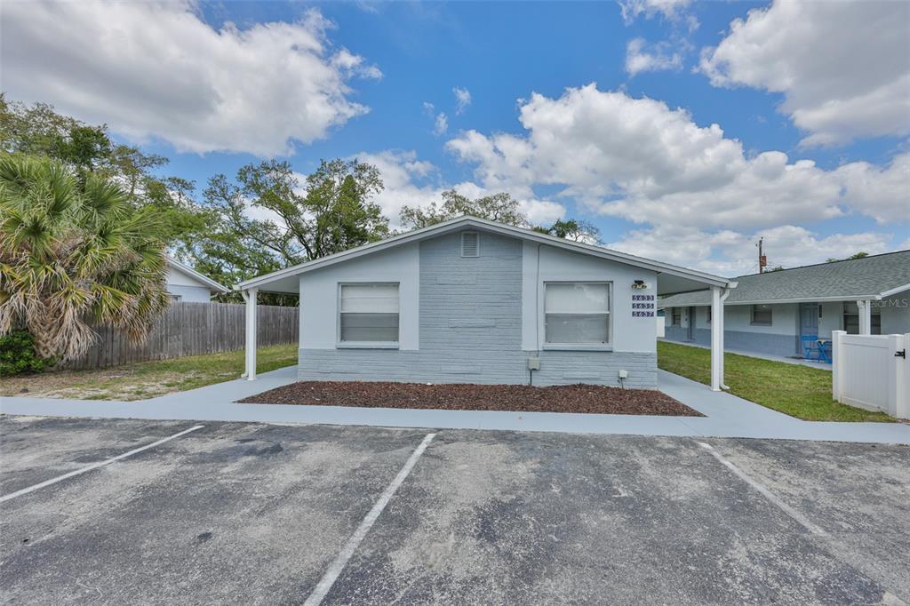 A single-story gray duplex building with a parking lot in the foreground — 5637 GOLDEN NUGGET DRIVE, HOLIDAY, FL