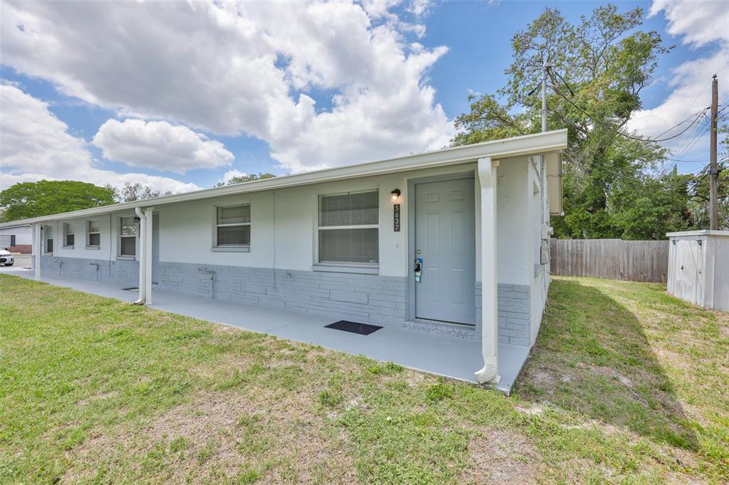A single-story building with a gray painted exterior, a covered porch, and a grassy yard — 5637 GOLDEN NUGGET DRIVE, HOLIDAY, FL
