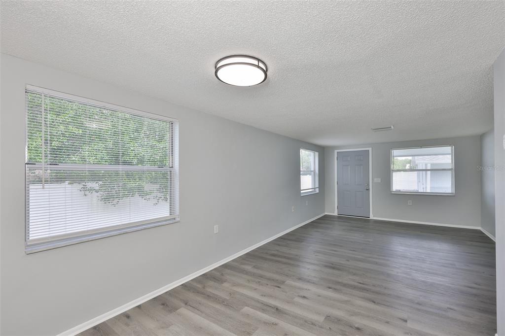 A living room with gray walls, wood-look flooring, a ceiling light, and three windows — 5637 GOLDEN NUGGET DRIVE, HOLIDAY, FL