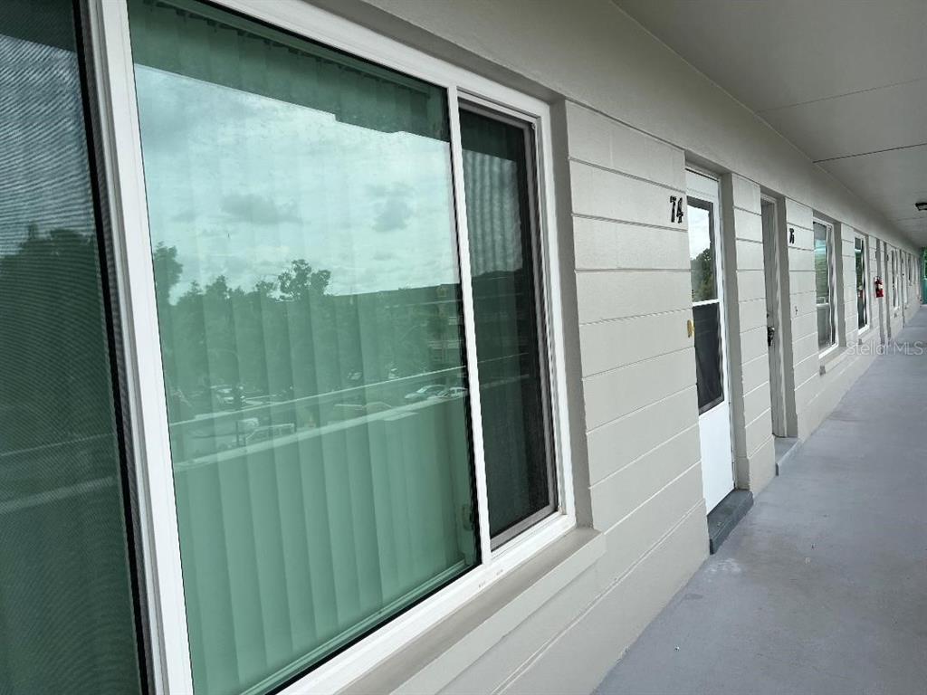An exterior view of a building with a walkway, windows, and numbered doors — 2370 JAMAICAN STREET UNIT 74, CLEARWATER, FL
