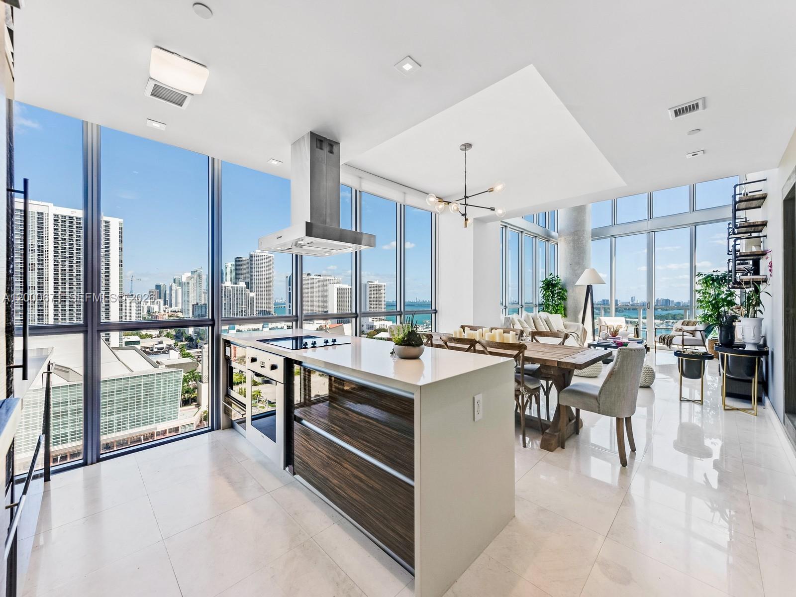 A modern kitchen and dining area with floor-to-ceiling windows overlooking a city skyline and water — 1100 Biscayne Blvd # 2105, Miami FL 33132, MIAMI, FL